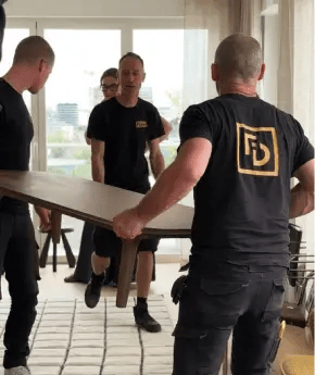 Des employés de Forma Design qui portent une table dans les locaux d'un client